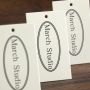 Custom off-white specialty paper clothing store hang tags, custom women's clothing labels with logo designs, and custom men's clothing hang tags.